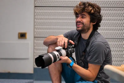 Fabio Mora holding a camera with a long lens at an event.
