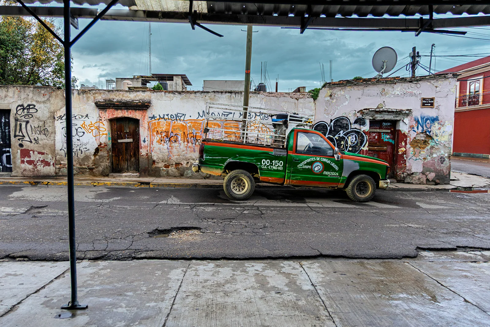 A brightly painted vehicle beside a weathered street building.