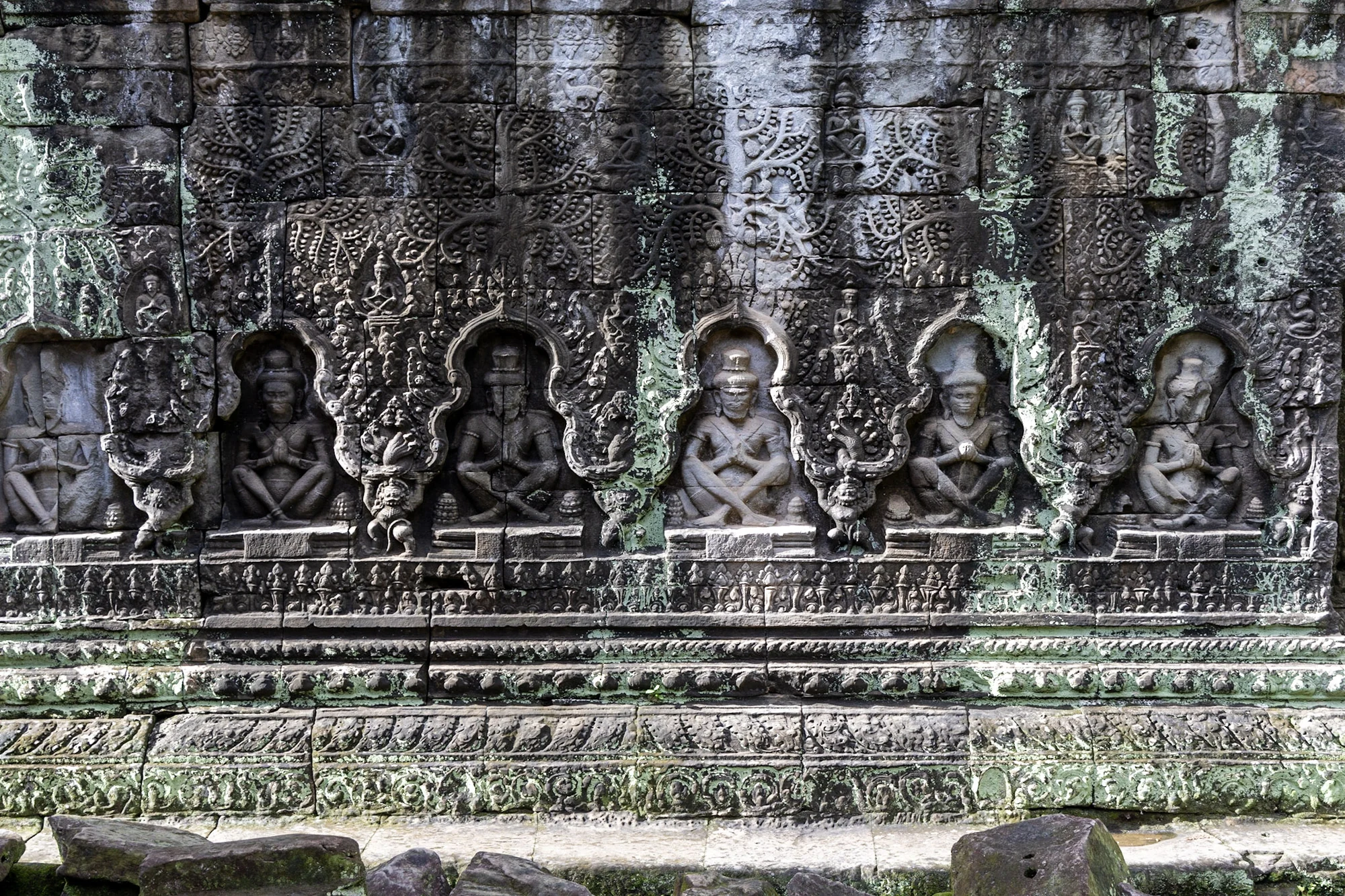 Seated figures carved into a richly decorated temple wall.