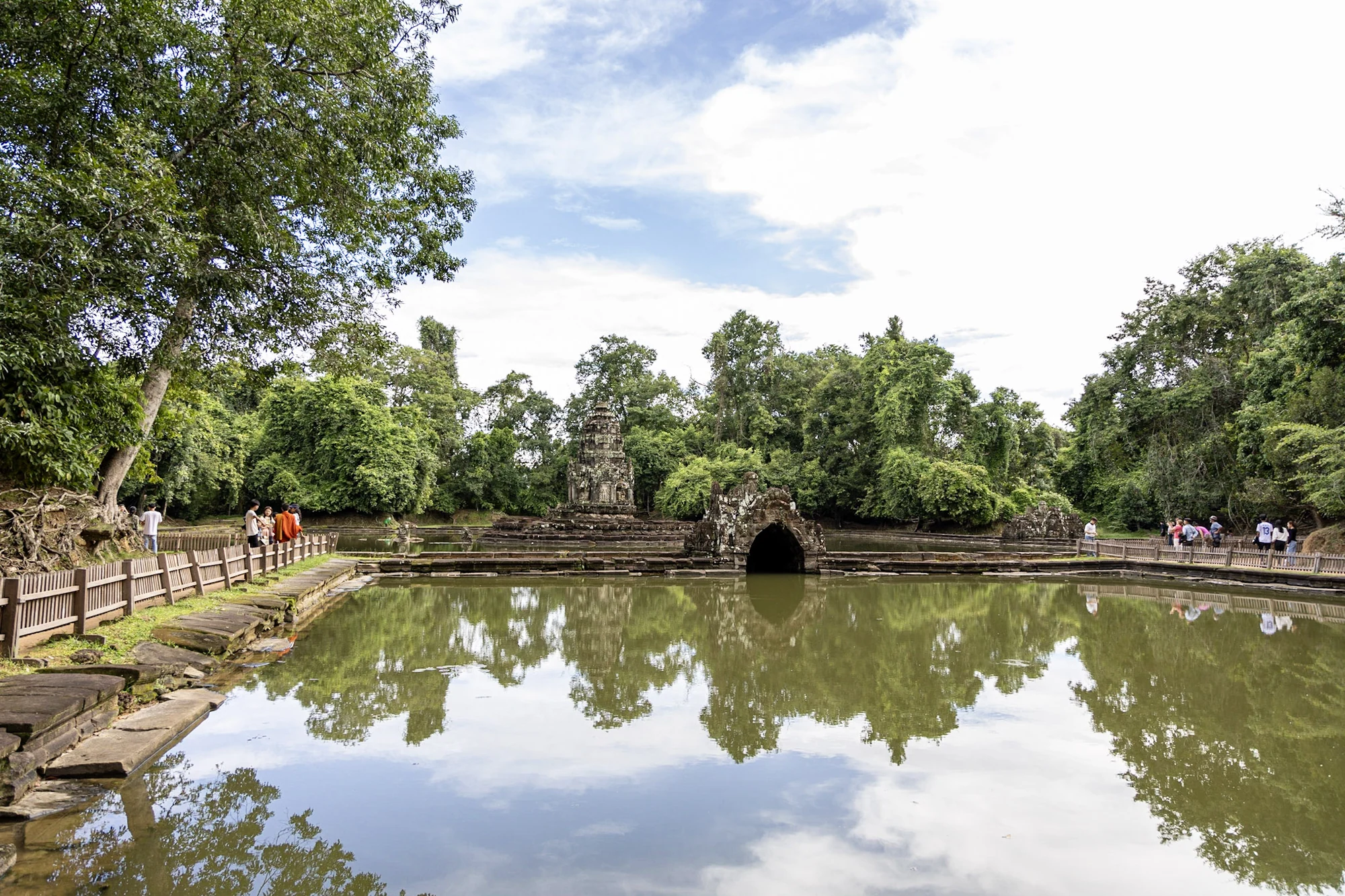 A temple pond reflecting trees and a small stone structure.