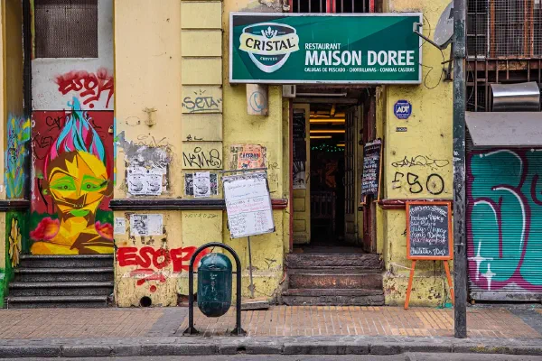 A graffiti-covered doorway beneath a Maison Dorée sign.