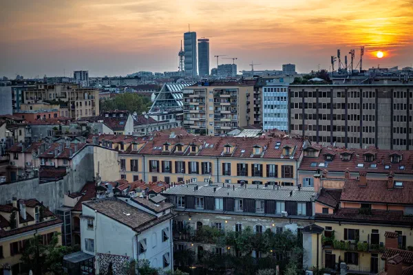 City rooftops and modern towers beneath a pastel sunset.