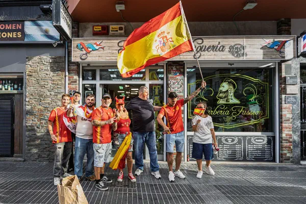 Football supporters waving a Spanish flag outside a bar.