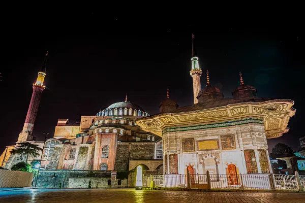 An illuminated building with minarets beneath a dark night sky.