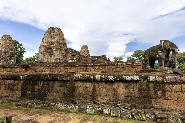 An elephant sculpture and brick temple towers beneath a blue sky.